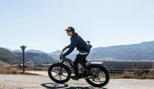 Een man rijdt op een Fiido Titan e-bike op een verharde weg.