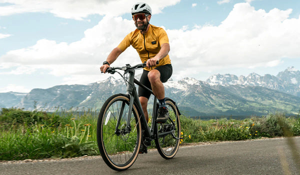 Een man rijdt op zijn Fiido C21 e-bike te midden van een berglandschap.