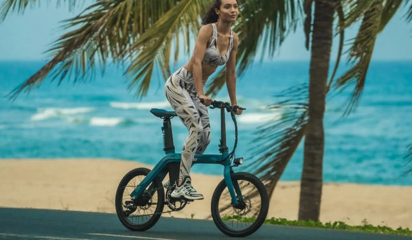 Vrouw rijdt op een elektrische fiets langs de zee