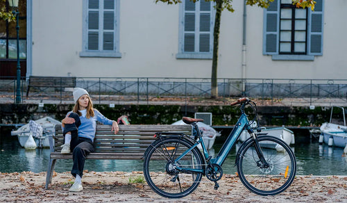 Een vrouw zittend op een bankje in het park kijkt naar de Fiido C11pro elektrische fiets