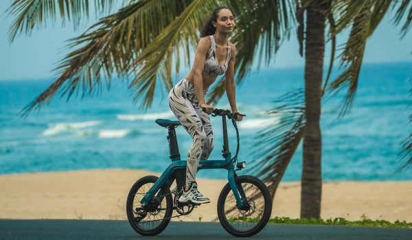 Een fitte vrouw rijdt op een fiido D11 elektrische fiets op het strand.