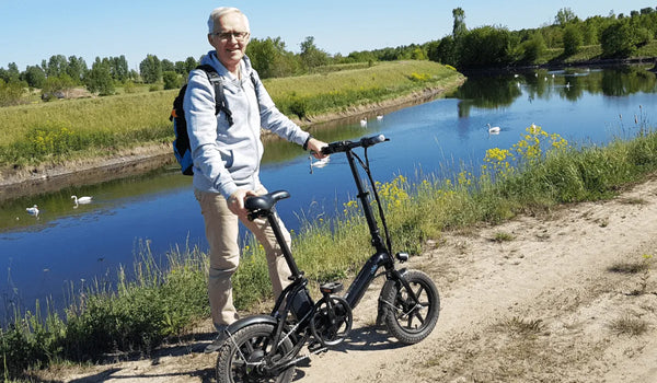 Een oudere man rijdt op een Fiido D3 Pro elektrische fiets langs de rivier.