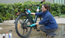 Een vrouw is haar elektrische fiets aan het onderhouden.