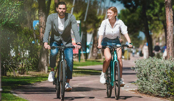 Een stel rijdt op Fiido C21 e-bikes door een park.