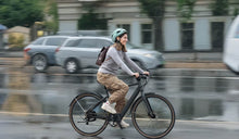 Een vrouw fietst in de regen naar haar werk op een Fiido C21 elektrische fiets.