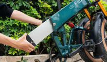 Een man verwijdert de externe accu van een Fiido M1 PRO elektrische fiets.