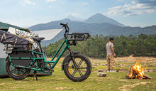 Fiido T2 elektrische bakfiets volgeladen met kampeeruitrusting op een bergcamping naast een tent en een kampvuur