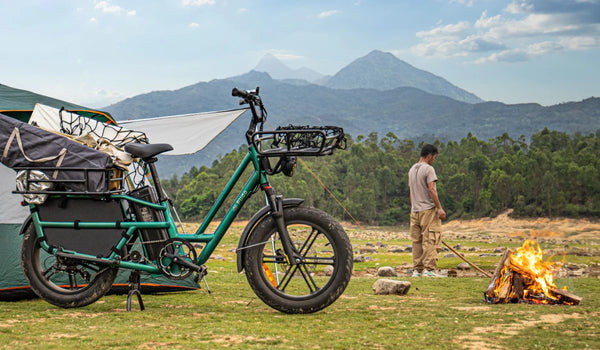 Fiido T2 elektrische bakfiets volgeladen met kampeeruitrusting op een bergcamping naast een tent en een kampvuur