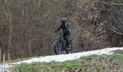 Een vrouw rijdt op een Fiido Titan elektrische fiets door de sneeuw.