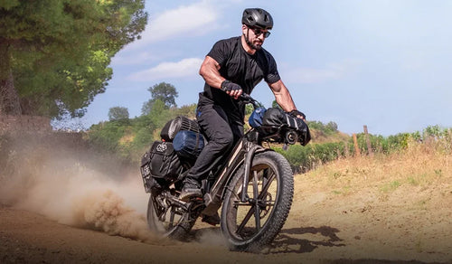 Een man rijdt met hoge snelheid door de bergen op een Fiido Titan fatbike.