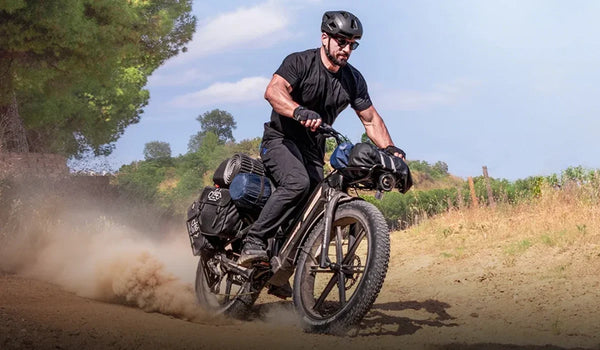 Een man rijdt met hoge snelheid door de bergen op een Fiido Titan fatbike.