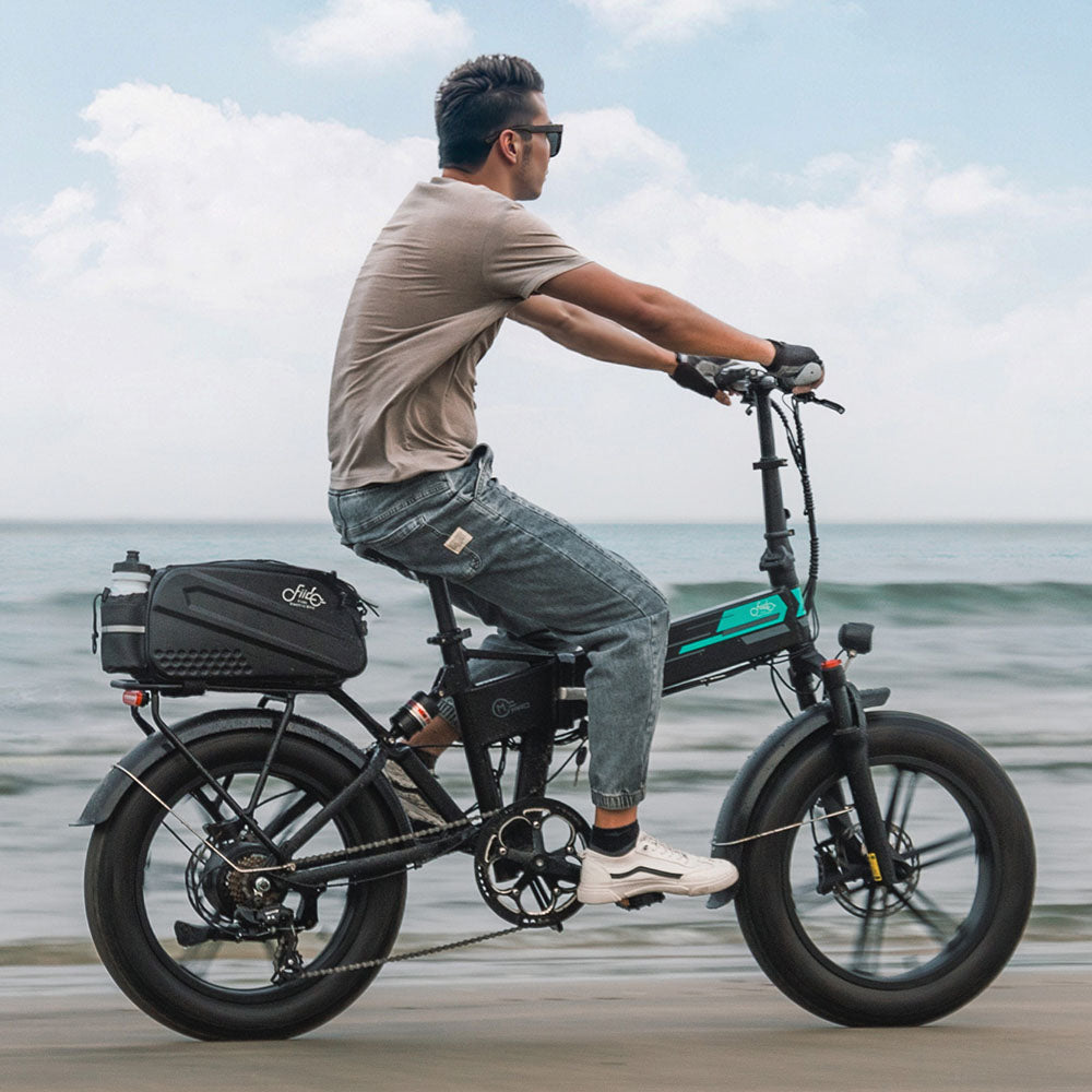 Man rijdt op de elektrische fiets Fiido M1pro met tas op het strand