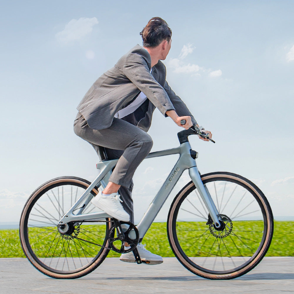 Zijaanzicht van een man die op een Fiido Air elektrische fiets van koolstofvezel rijdt op de weg